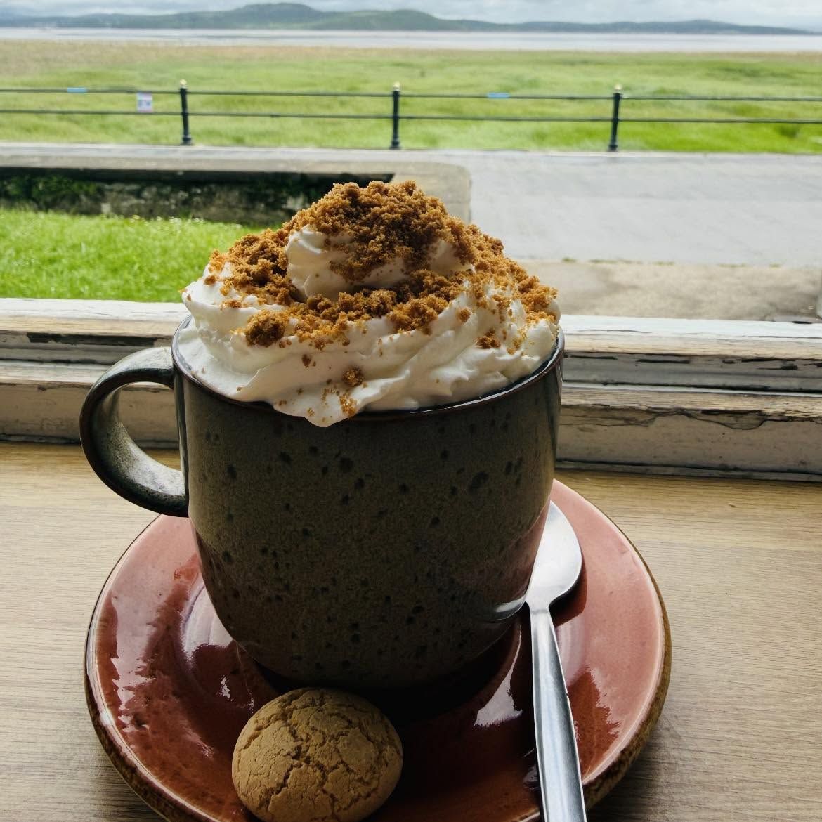 Hot chocolate with cream and biscuit crumb, looking out over Morecambe Bay